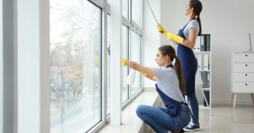 Janitors washing window in office