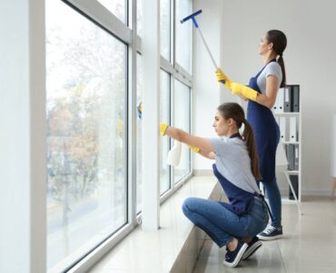 Janitors washing window in office