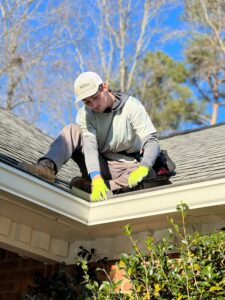 person cleaning gutter on rooftop