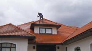 man at the top of house painting roof